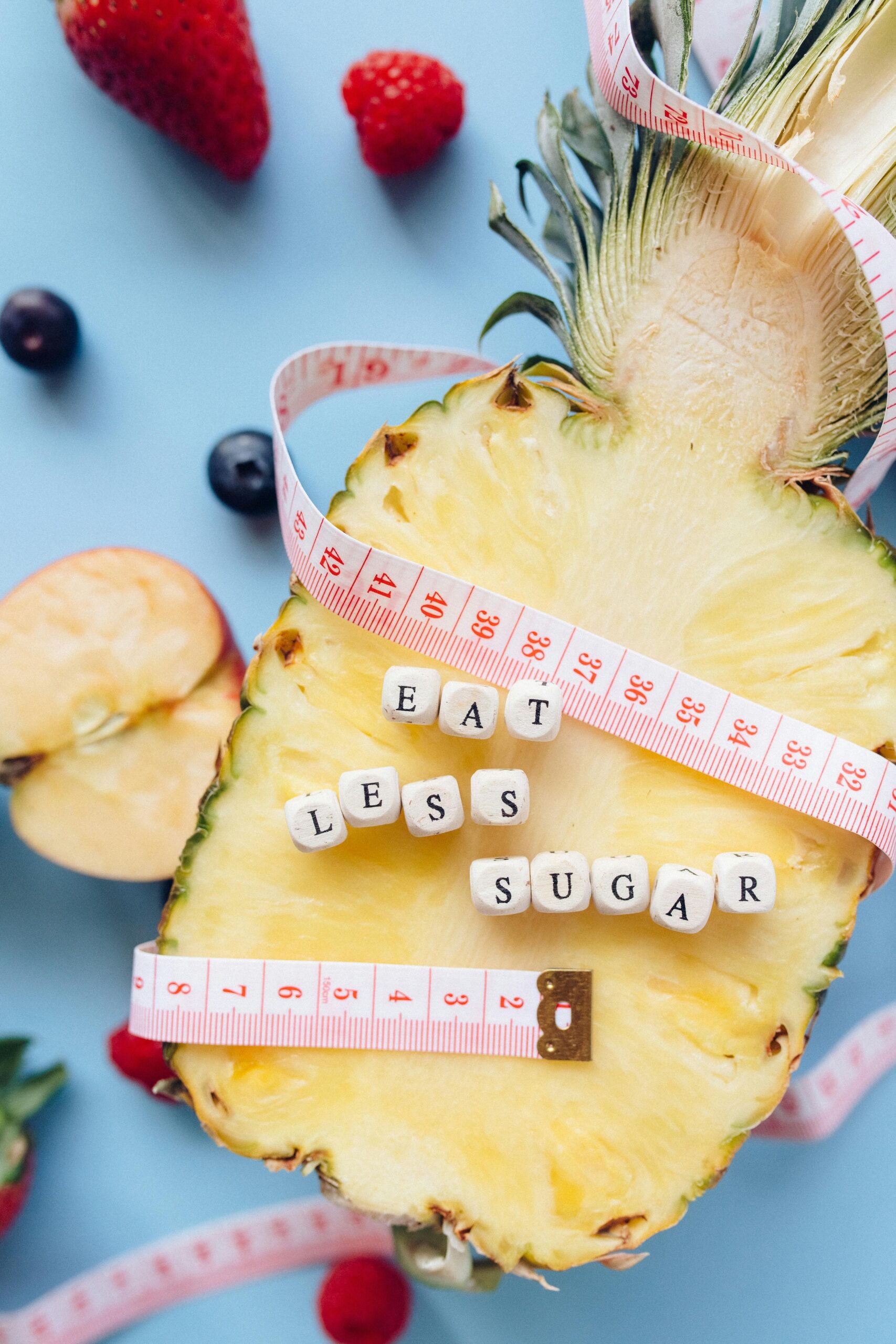 Fresh pineapple with a tape measure and the phrase 'Eat Less Sugar' promoting healthy eating habits.
